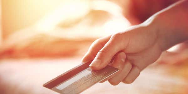 A person holding a cashback credit card in their hand and using this for payment