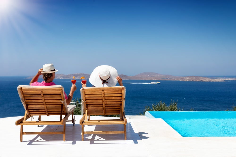 A couple are on holiday sitting in deck chairs and admiring the sea view. 
