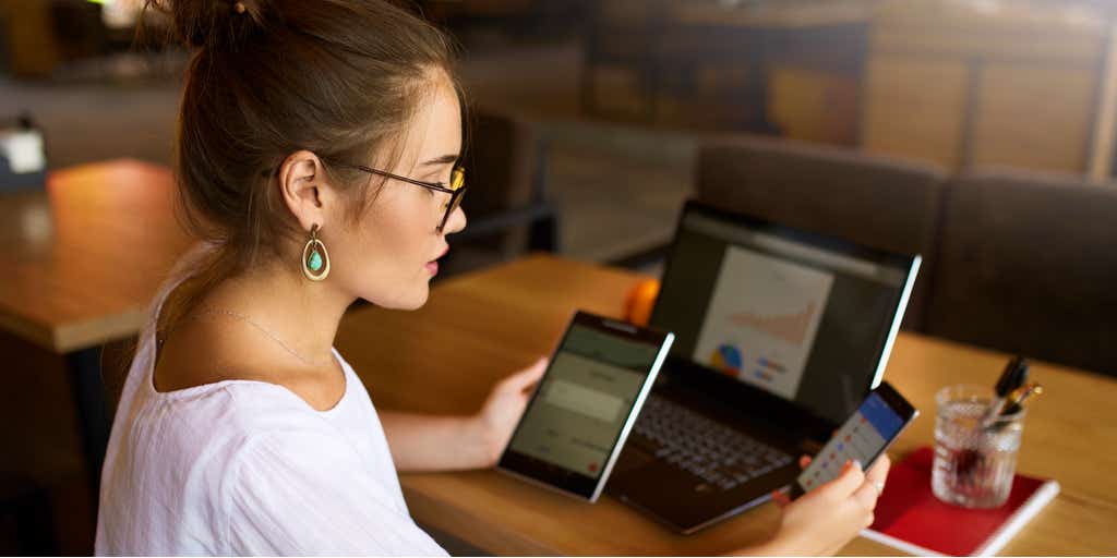 Image of woman working on her desk looking at iPad, laptop and smart phone