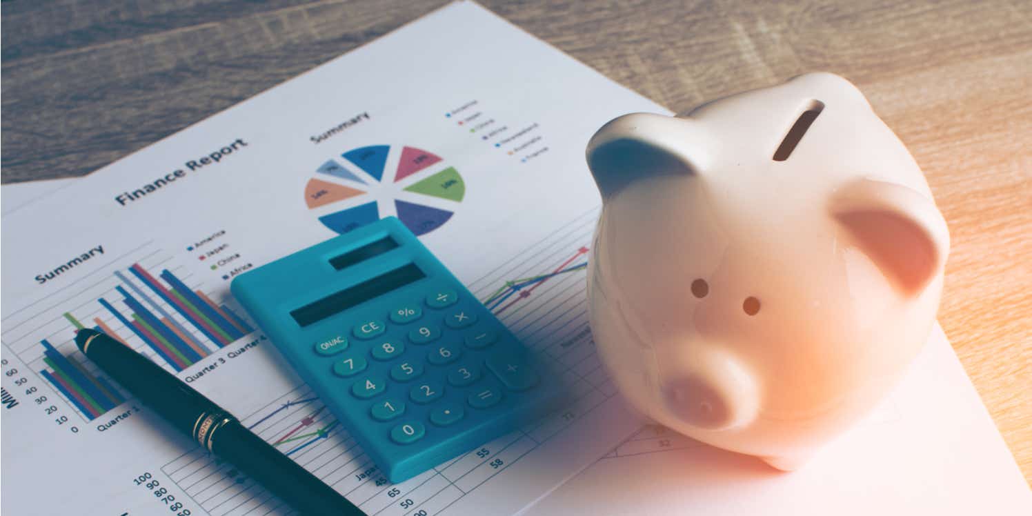 Piggy bank with financial documents and calculator on desk. 