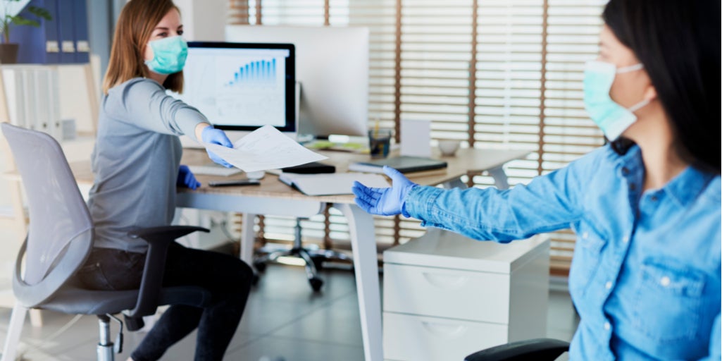 Two people in office passing documents with keeping a distance