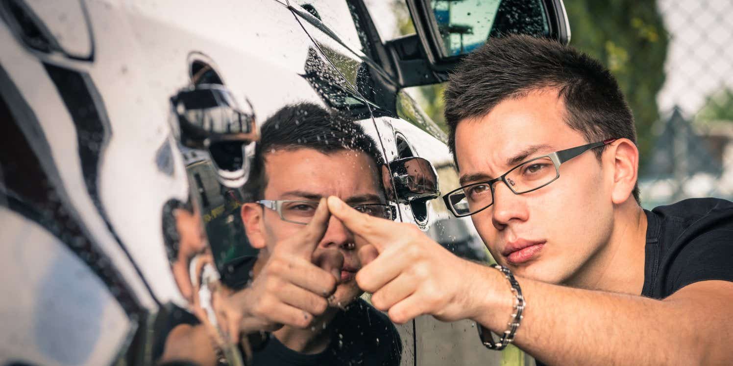 Man inspecting car for scratches