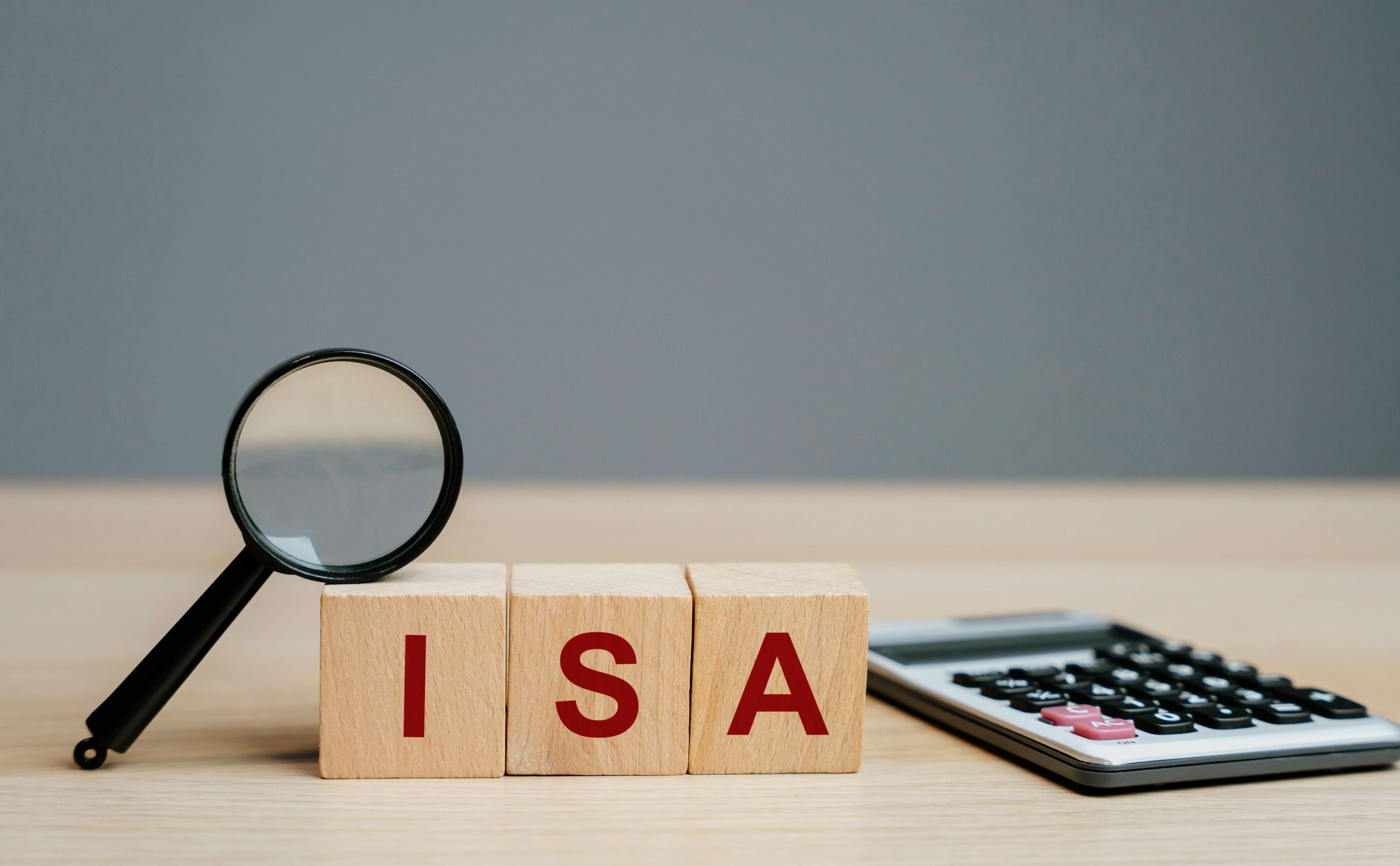 Magnifying glass, wooden blocks with ISA written on them and a calculator sitting on a table. 