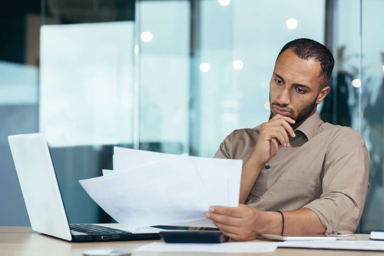 Businessman sits at a desk and contemplates his paperwork