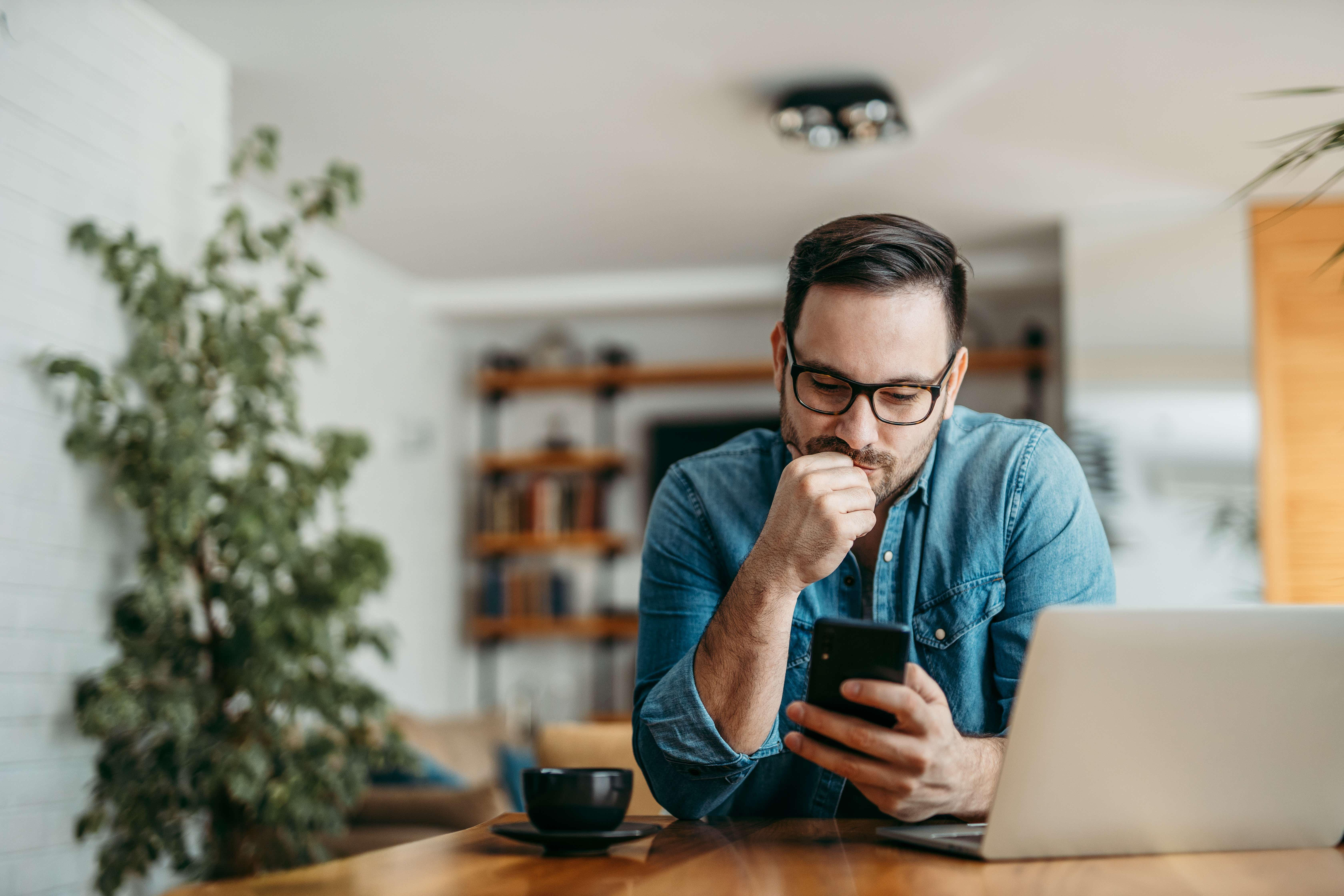 Bearded man with glasses looking at his phone