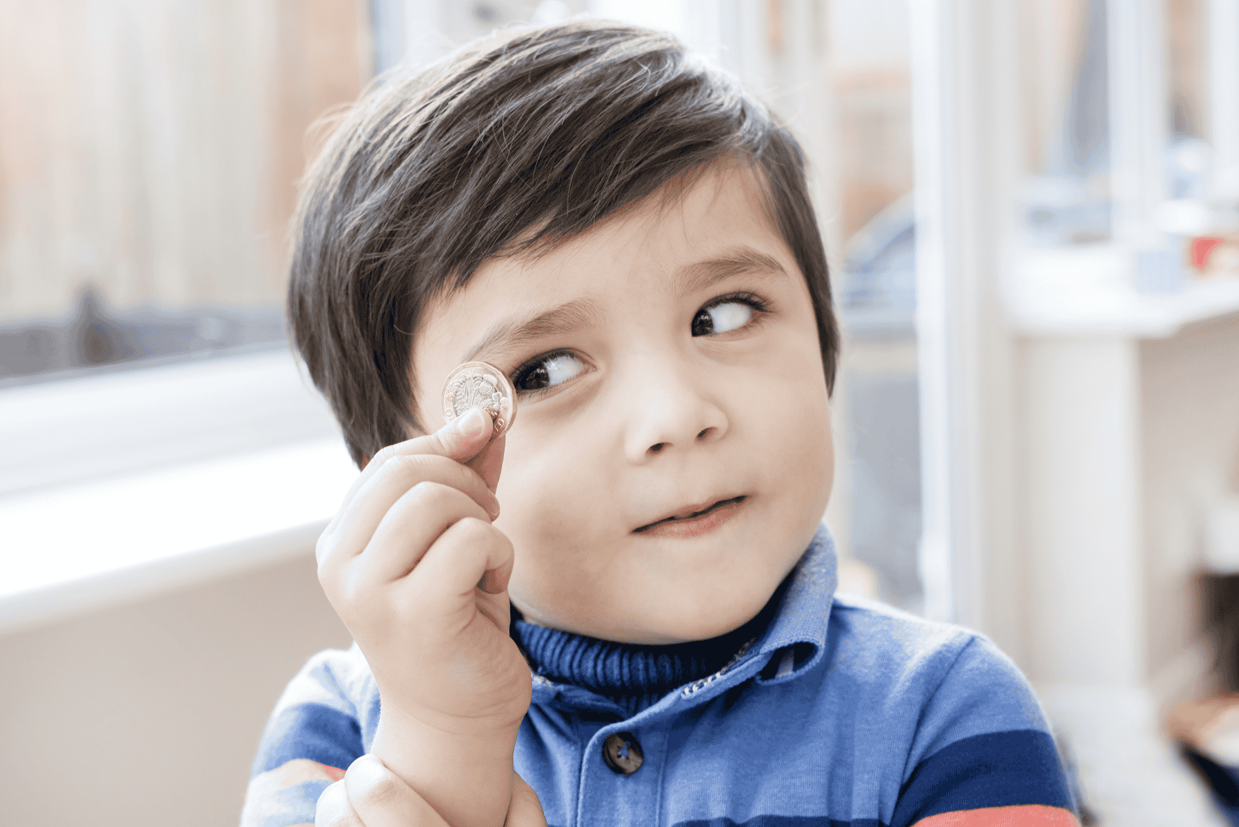 A cute young kid eyeballing a one pound coin