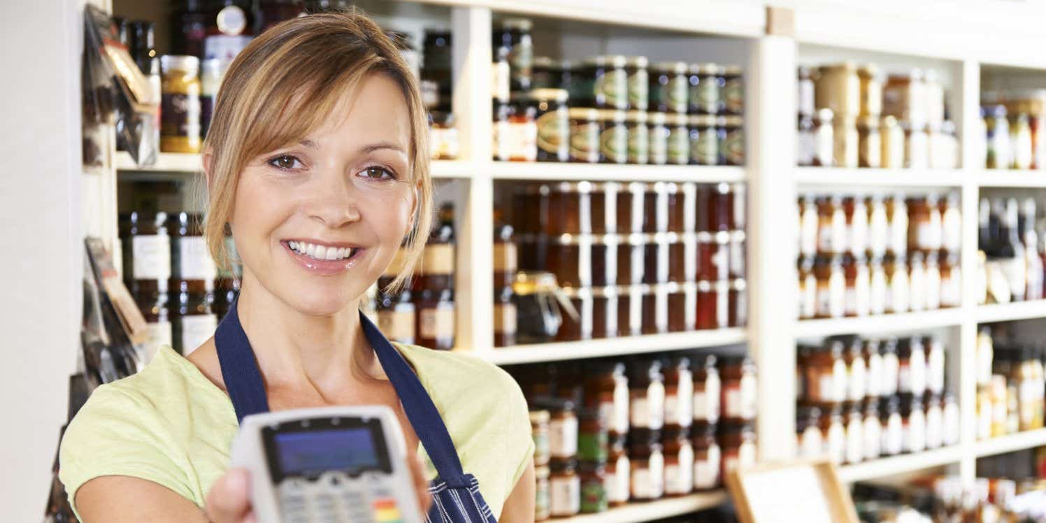 Women in food store holding card machine