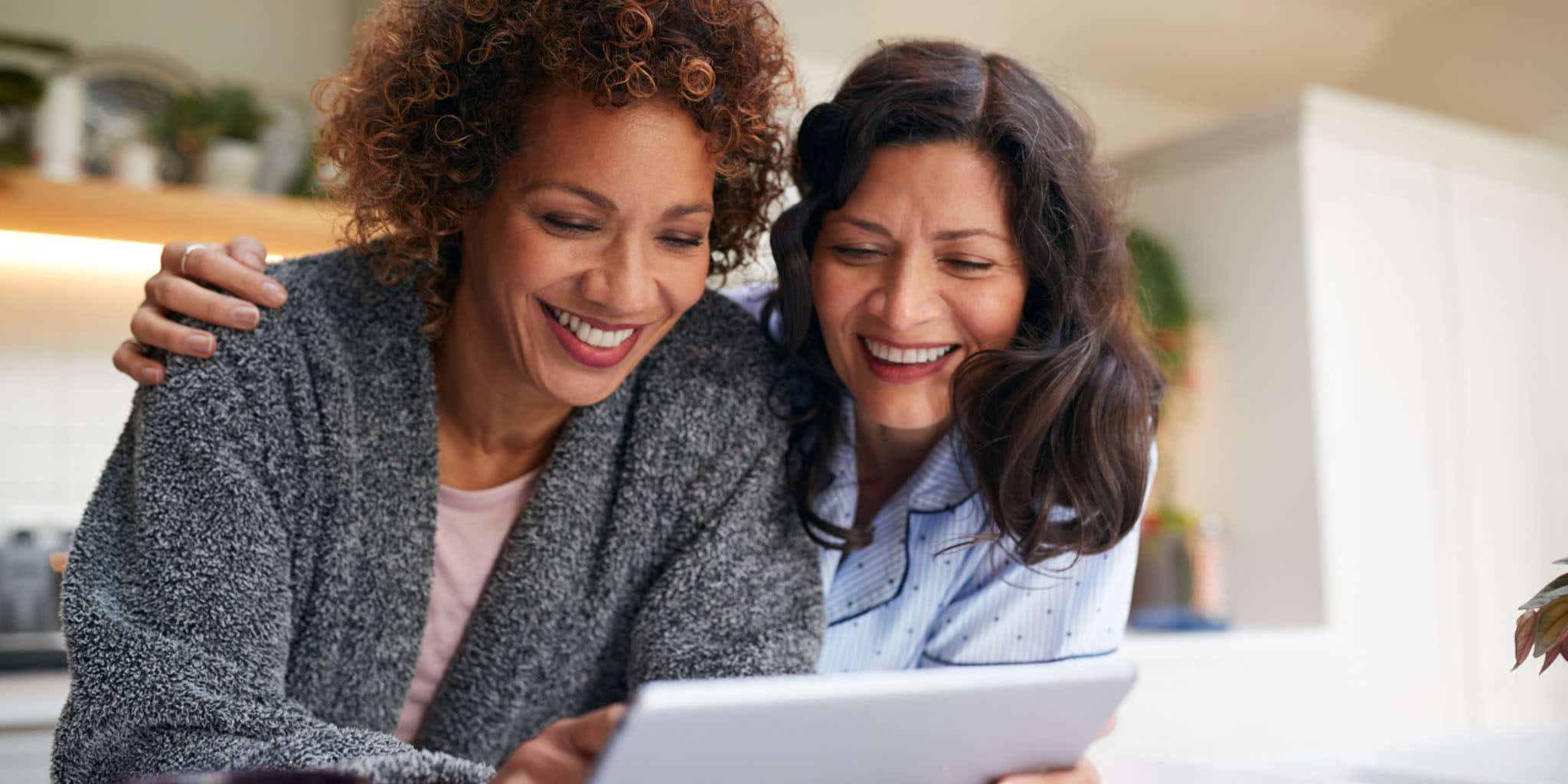 Mature same sex female couple at Home in kitchen with digital tablet