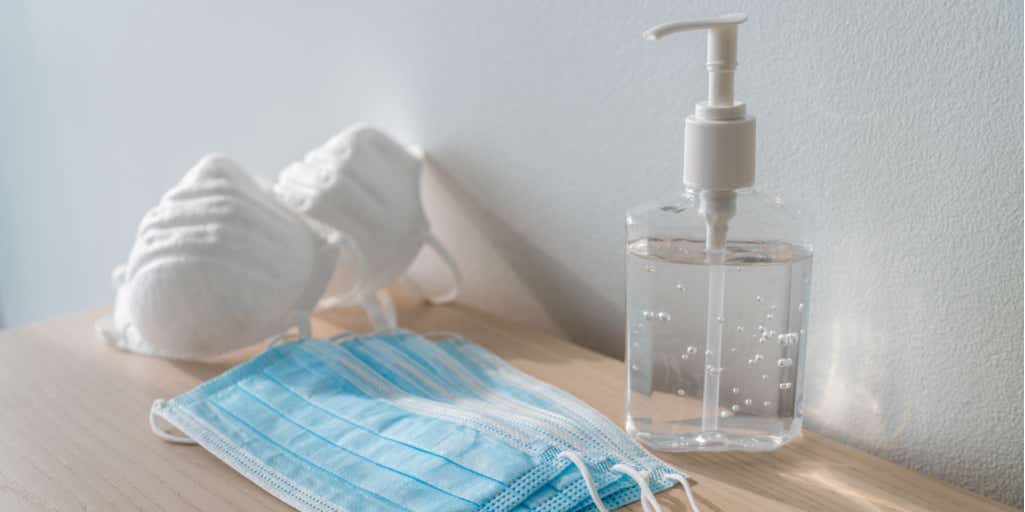 Photograph of face masks and hand sanitiser on a wooden table