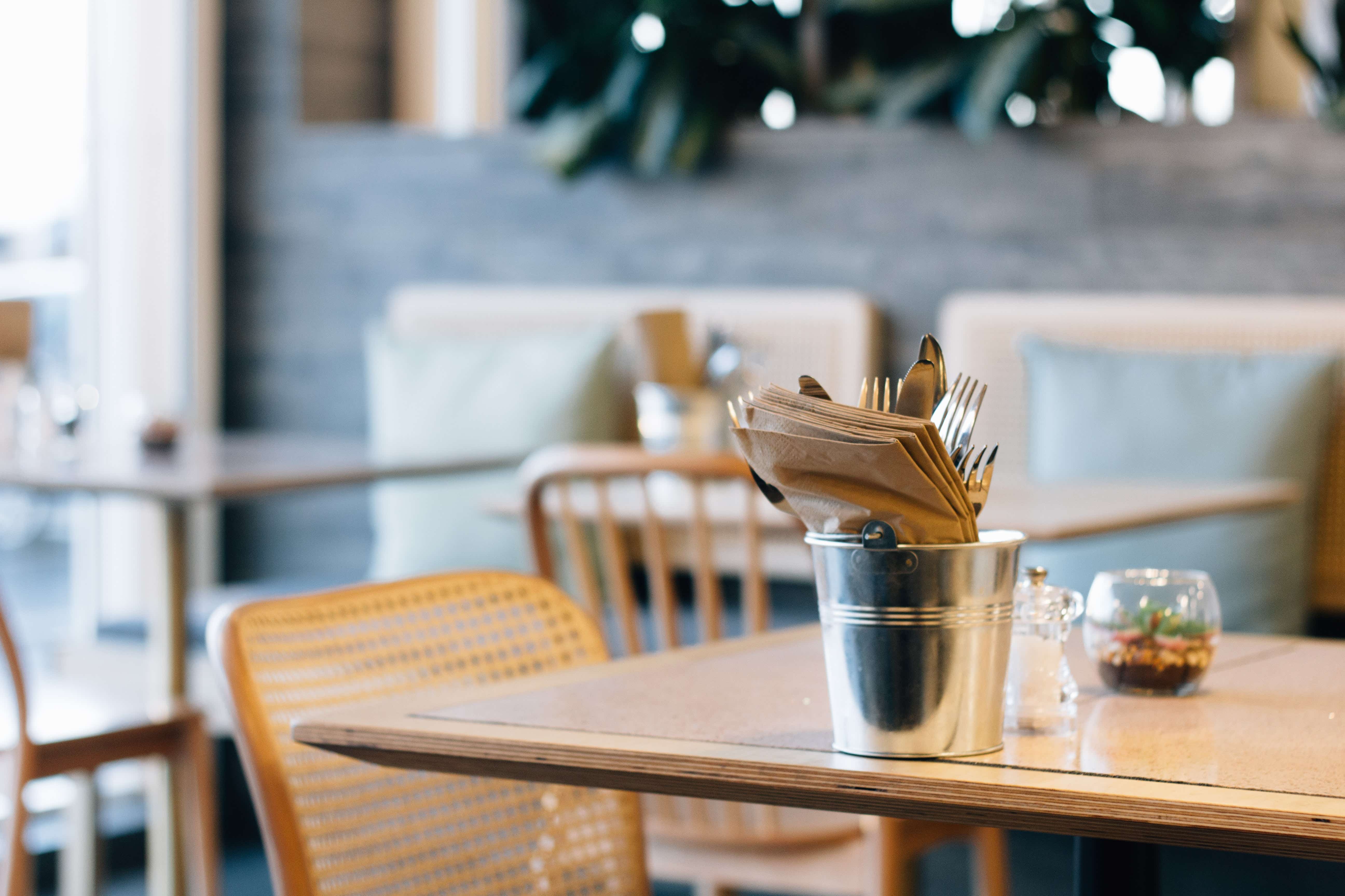 A picture of a restaurant with cutlery and condiments on a table.