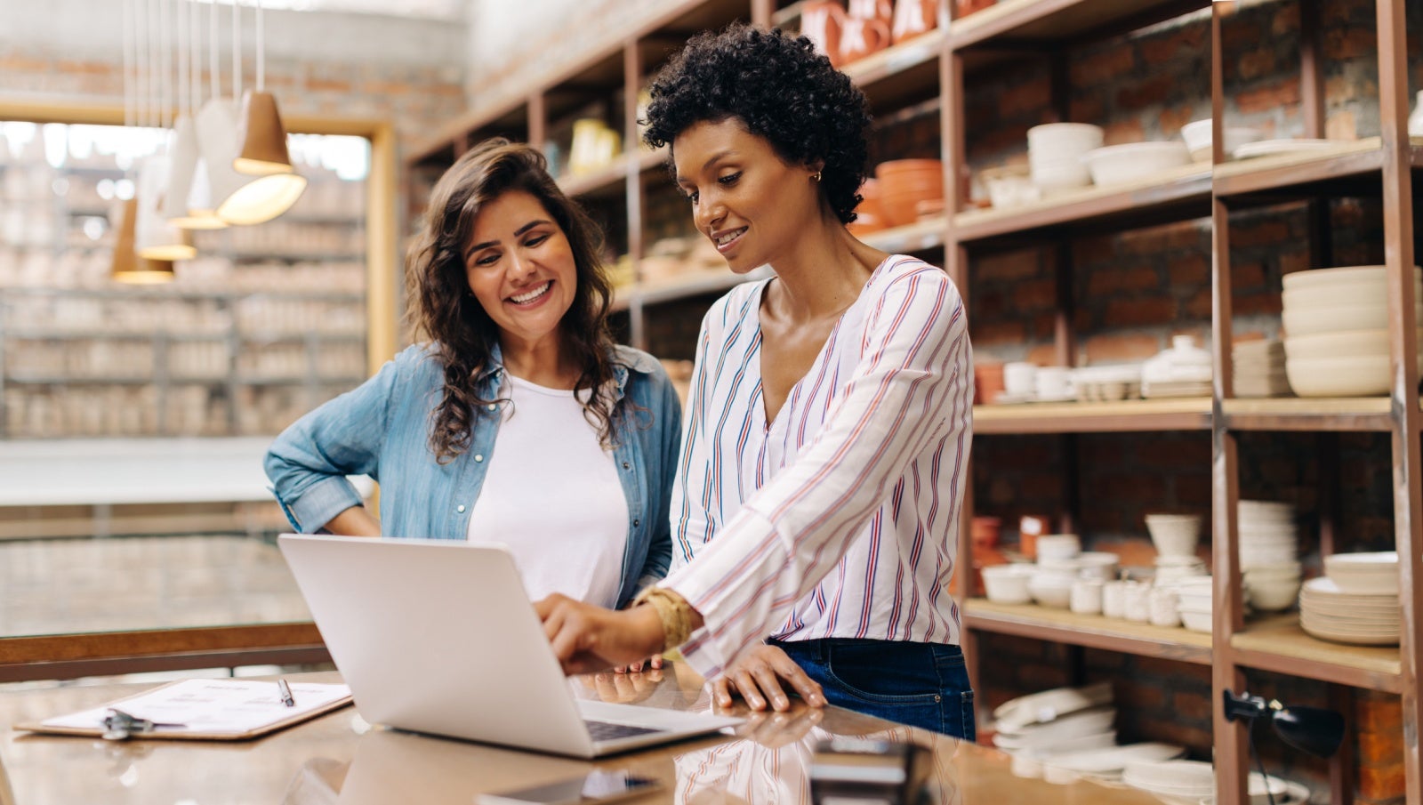 Partners in a ceramics business work together on a laptop.