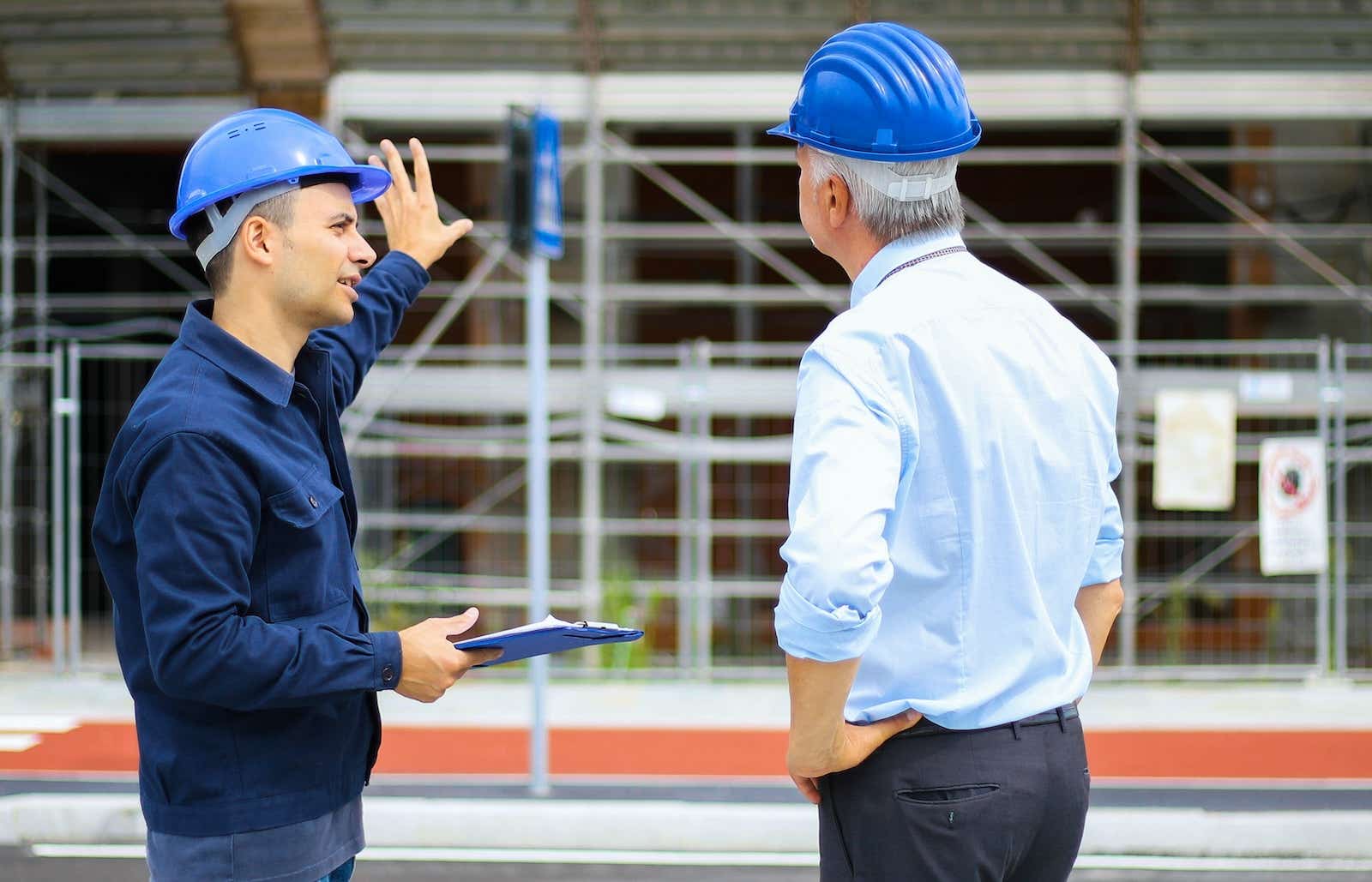 Foreman explains project progress to his biss at a building site.